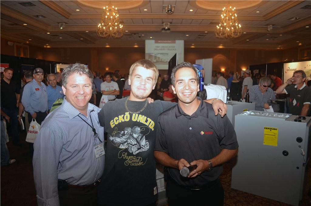 Allied Air Enterprises' J. Alain Boudreau (l) and Noble's Vince Baggetta (r) pose with David Escott of Comfort Heating after he was declared the winner of an Armstrong furnace during one of seven furnace draws.