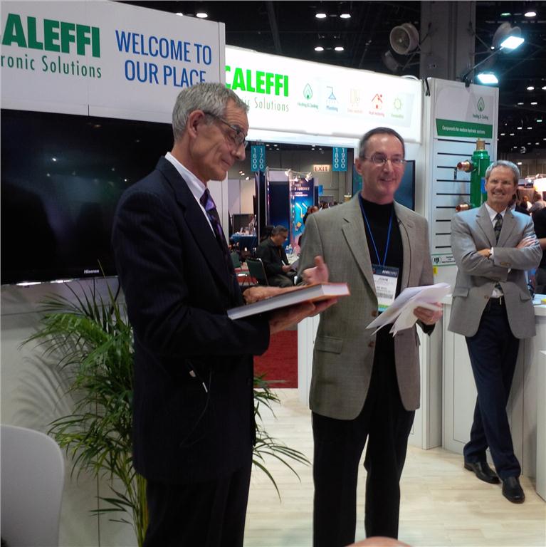 John Siegenthaler (c) at his book launch at AHR where he announced that he was dedicating his book, Heating with Renewable Energy, to Bob (Hot Rod) Rohr (l). Mark Olson, chief executive officer and general manager at Caleffi North America, Inc., looks on.