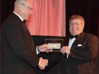 Gaetan Beaulieu (l), MCA Canada's past chairman, passes the buck to Del Pawliuk (r), president, MCA Canada, at the National Conference closing gala.