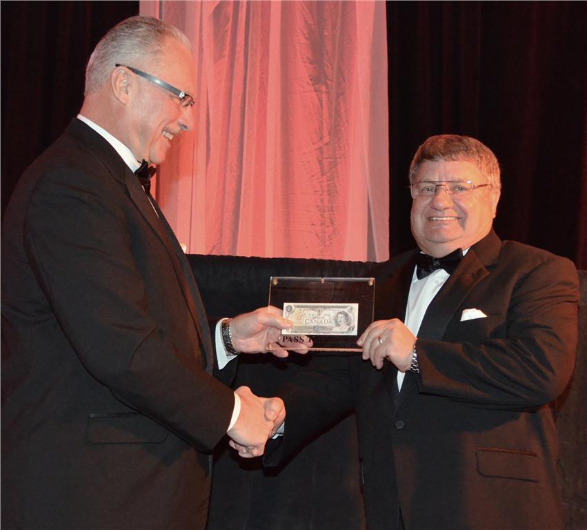 Gaetan Beaulieu (l), MCA Canada's past chairman, passes the buck to Del Pawliuk (r), president, MCA Canada, at the National Conference closing gala.