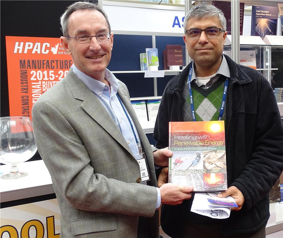 John Siegenthaler (l), author of Heating With Renewable Energy, presents a copy of the book to Joydeep Bose of EB Air Control Inc. on the final day of the CMPX show.